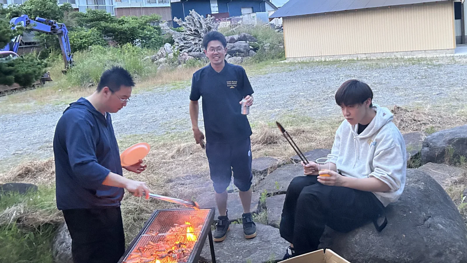 屋外でBBQを囲みながら会話する社員